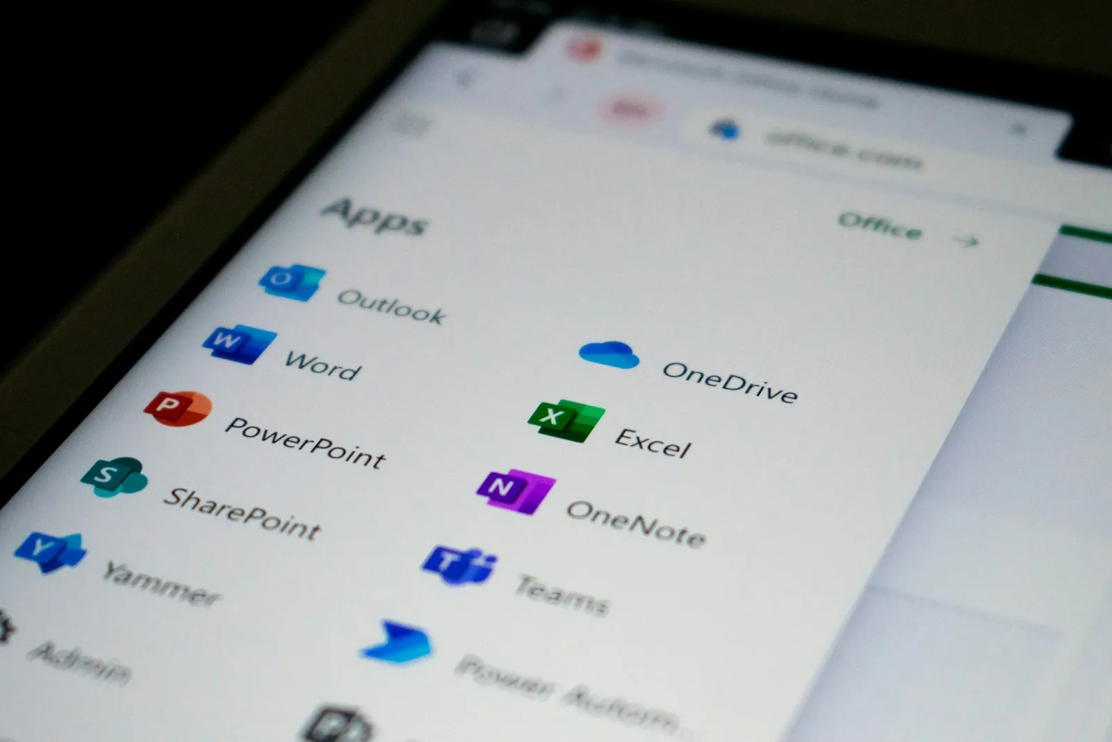 An employee working in Outlook and Word on a laptop at an office desk