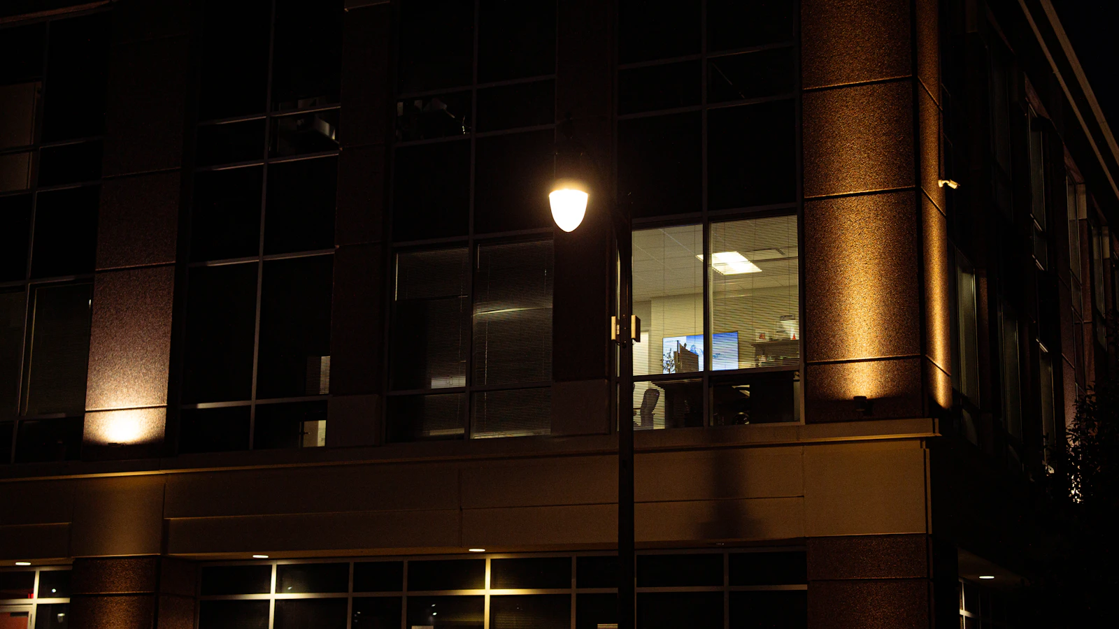 An office building at night with lights on in one window