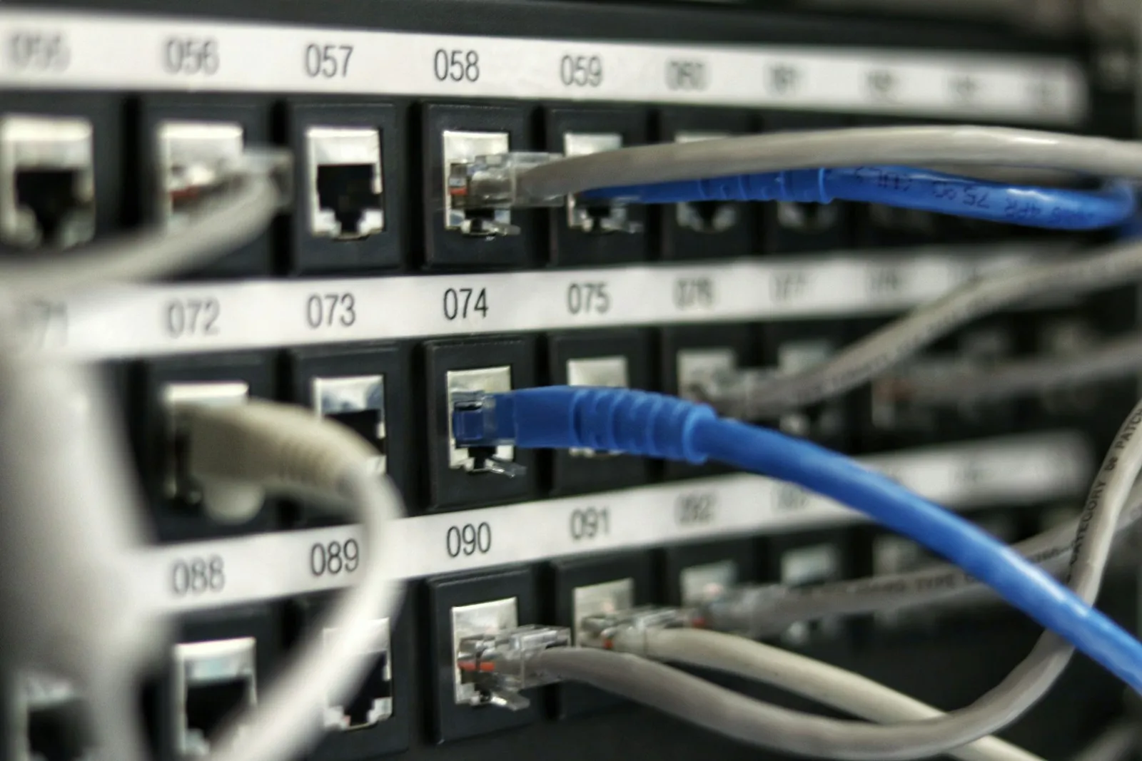 An IT technician reviewing a vulnerability scan report on a laptop next to a network rack