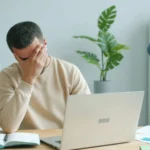 An office worker looking at a computer screen with a frustrated expression in a small business office