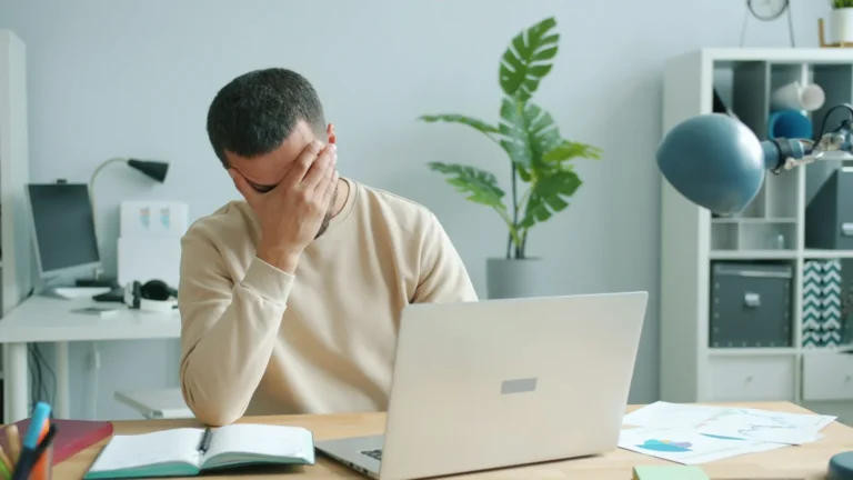 An office worker looking at a computer screen with a frustrated expression in a small business office