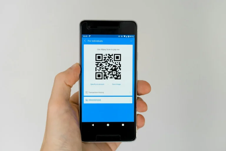 Close-up of a person holding a smartphone up to scan a printed QR code