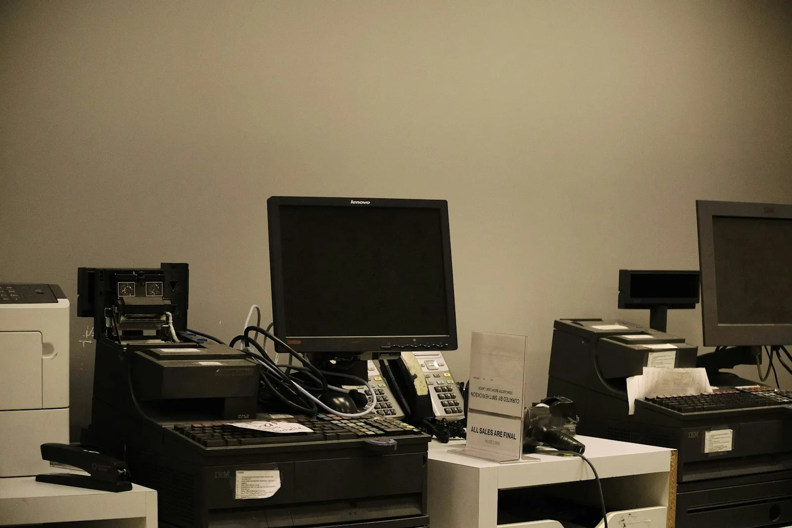 A stack of older laptops next to a new laptop being set up on an office desk