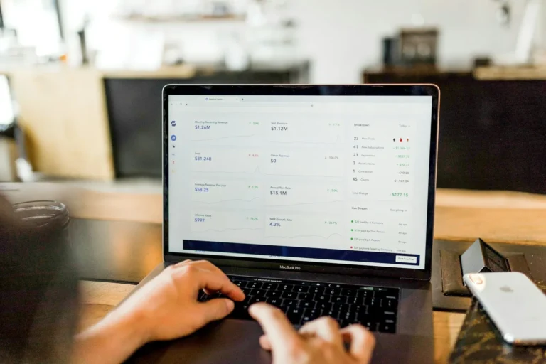 An office worker at a desk reviewing an invoice email on a laptop before approving a payment