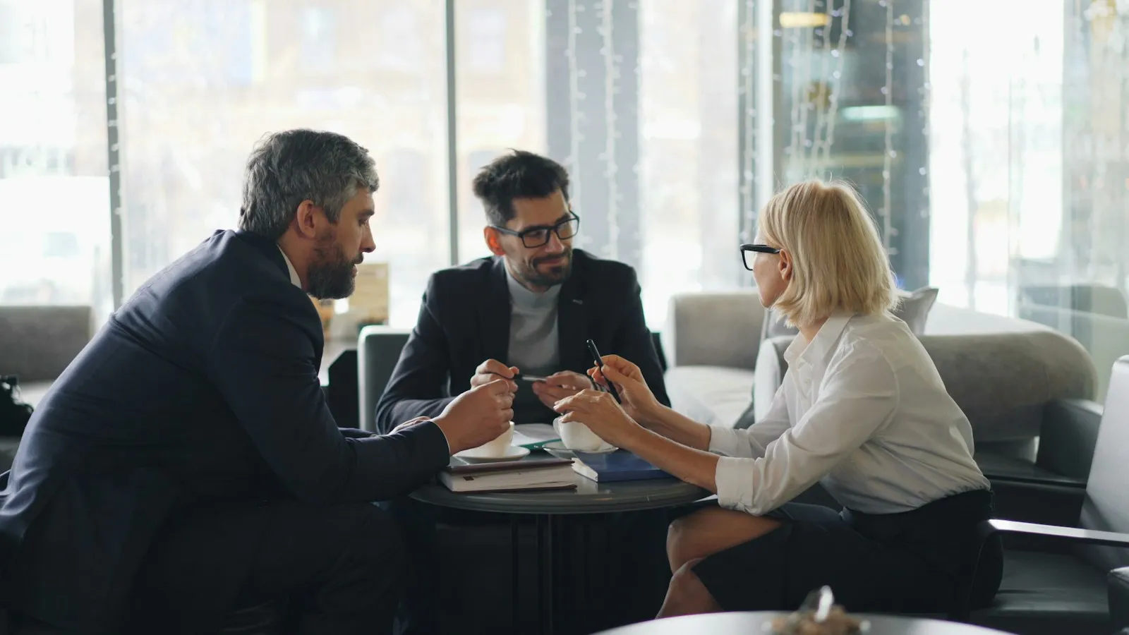 Three colleagues talking at a meeting table