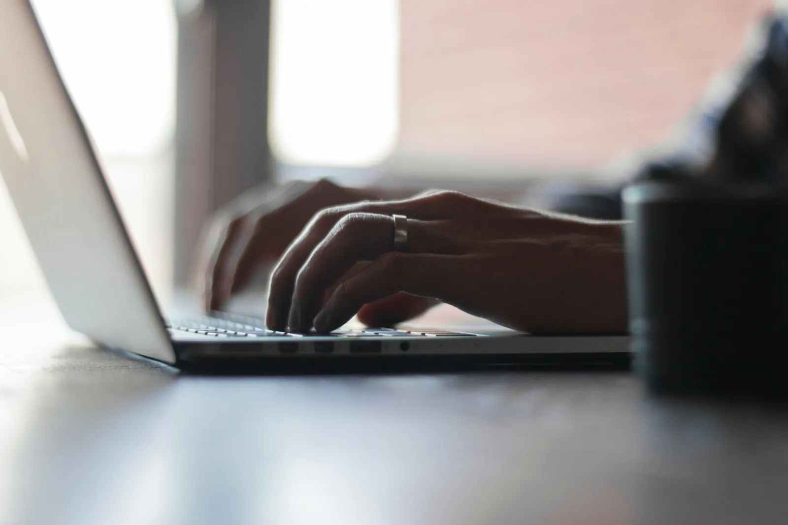 Close-up of a person typing on a laptop at a desk