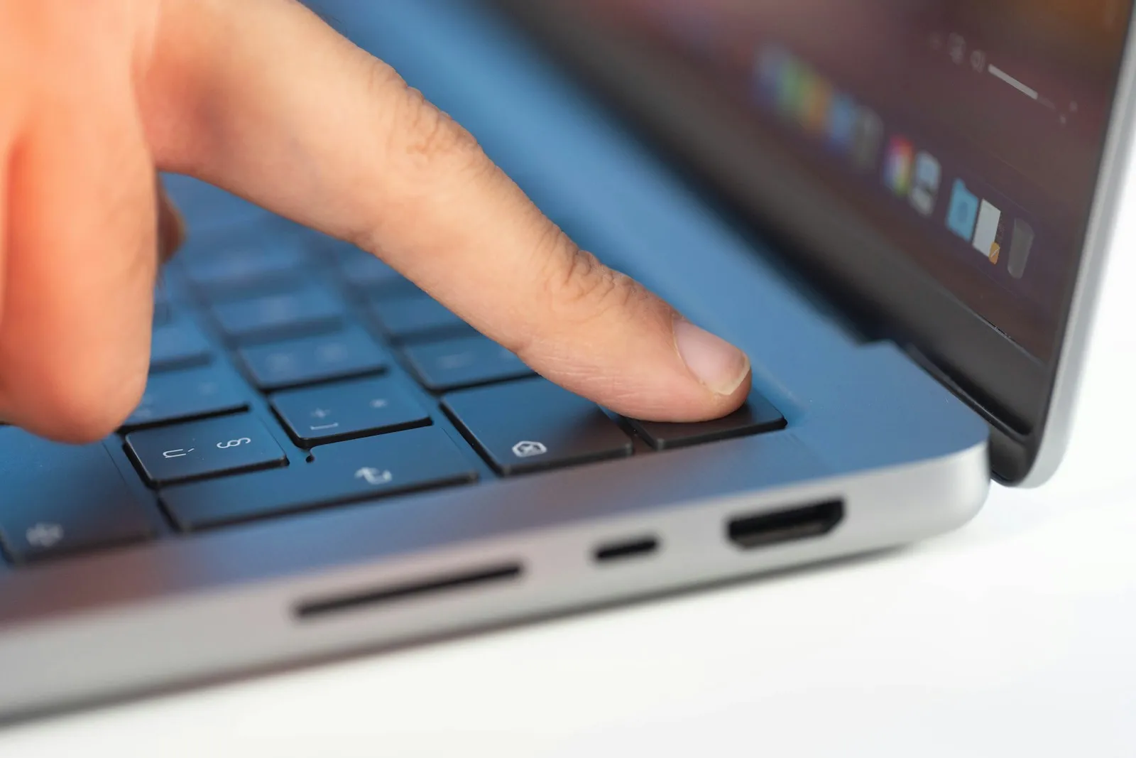 A person signing in to a laptop with a fingerprint reader and a smartphone nearby