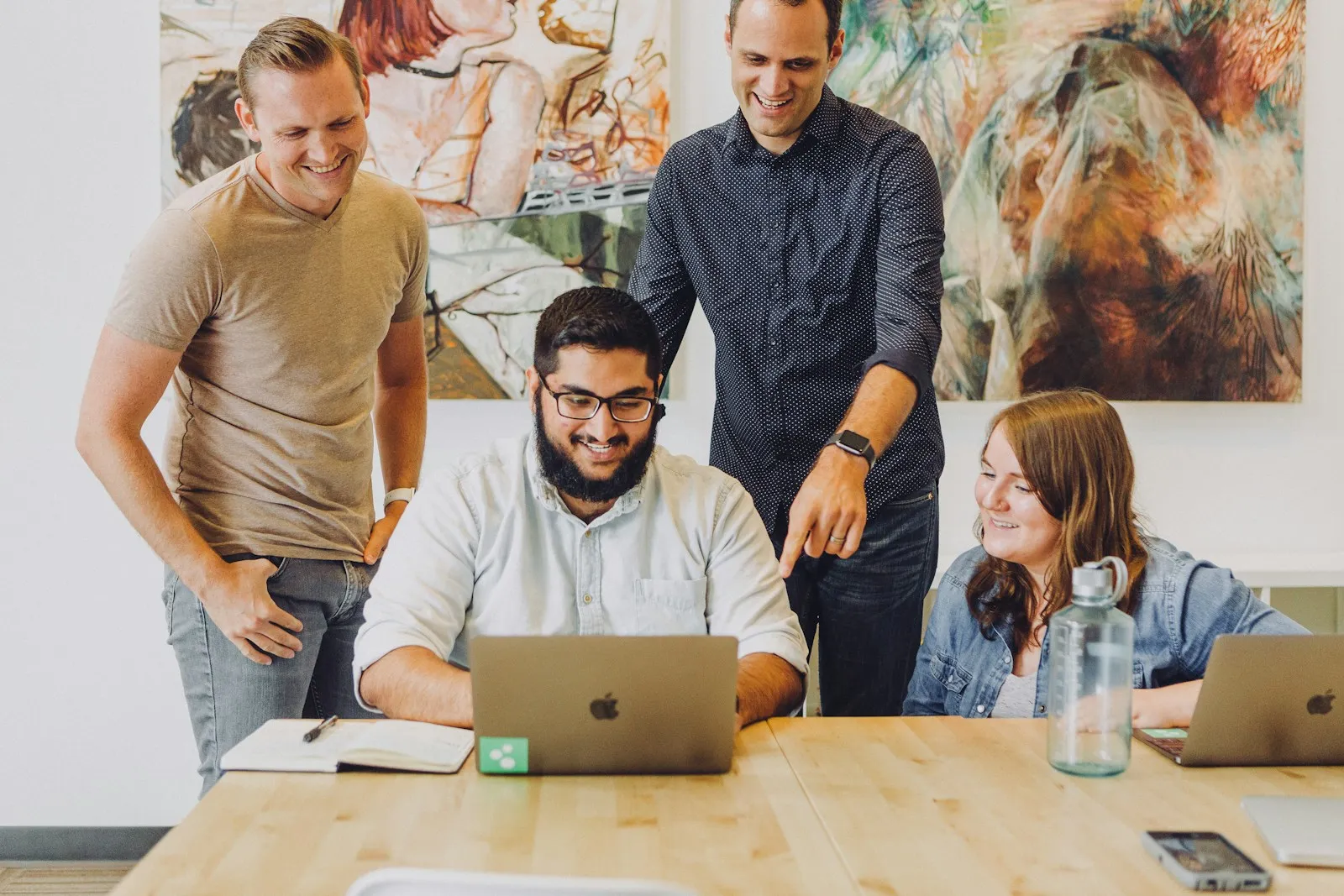 A small group of office employees gathered around a laptop during a training session