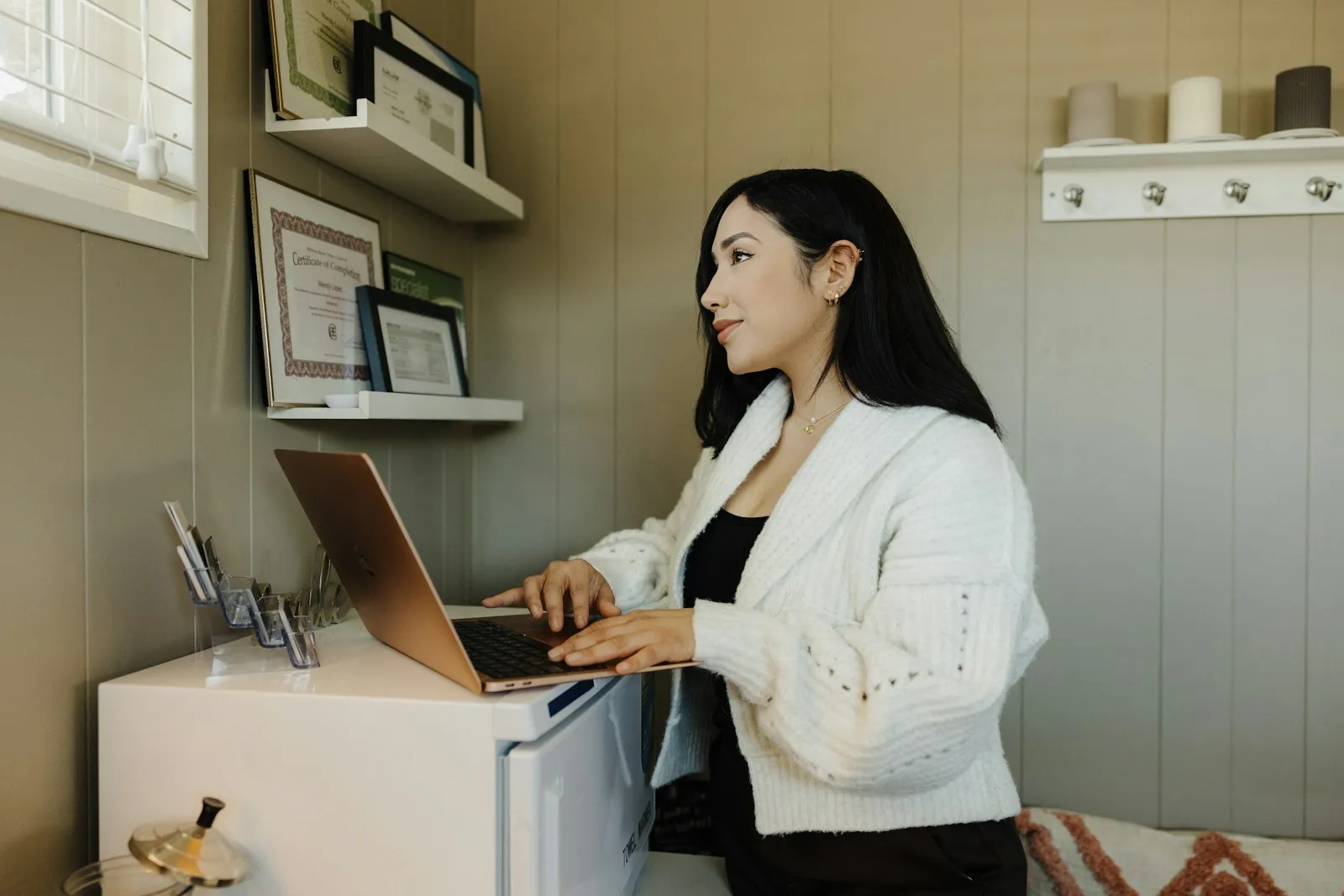 Woman working on a laptop at a small office desk