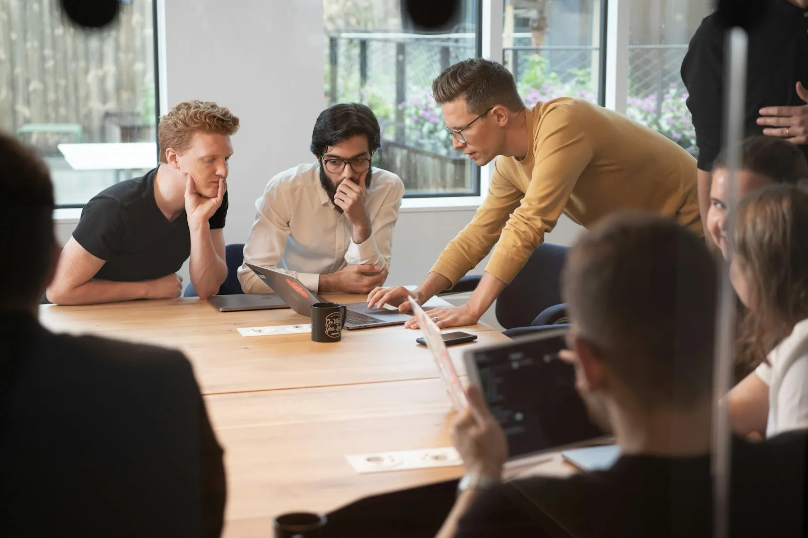 Coworkers meeting around a table with laptops