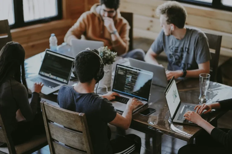 Small office team working together at laptops around a table