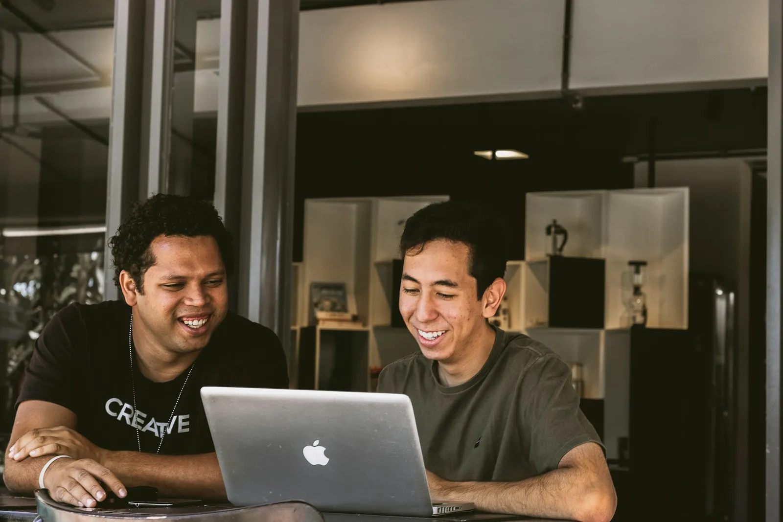 Two coworkers smiling while working on a laptop