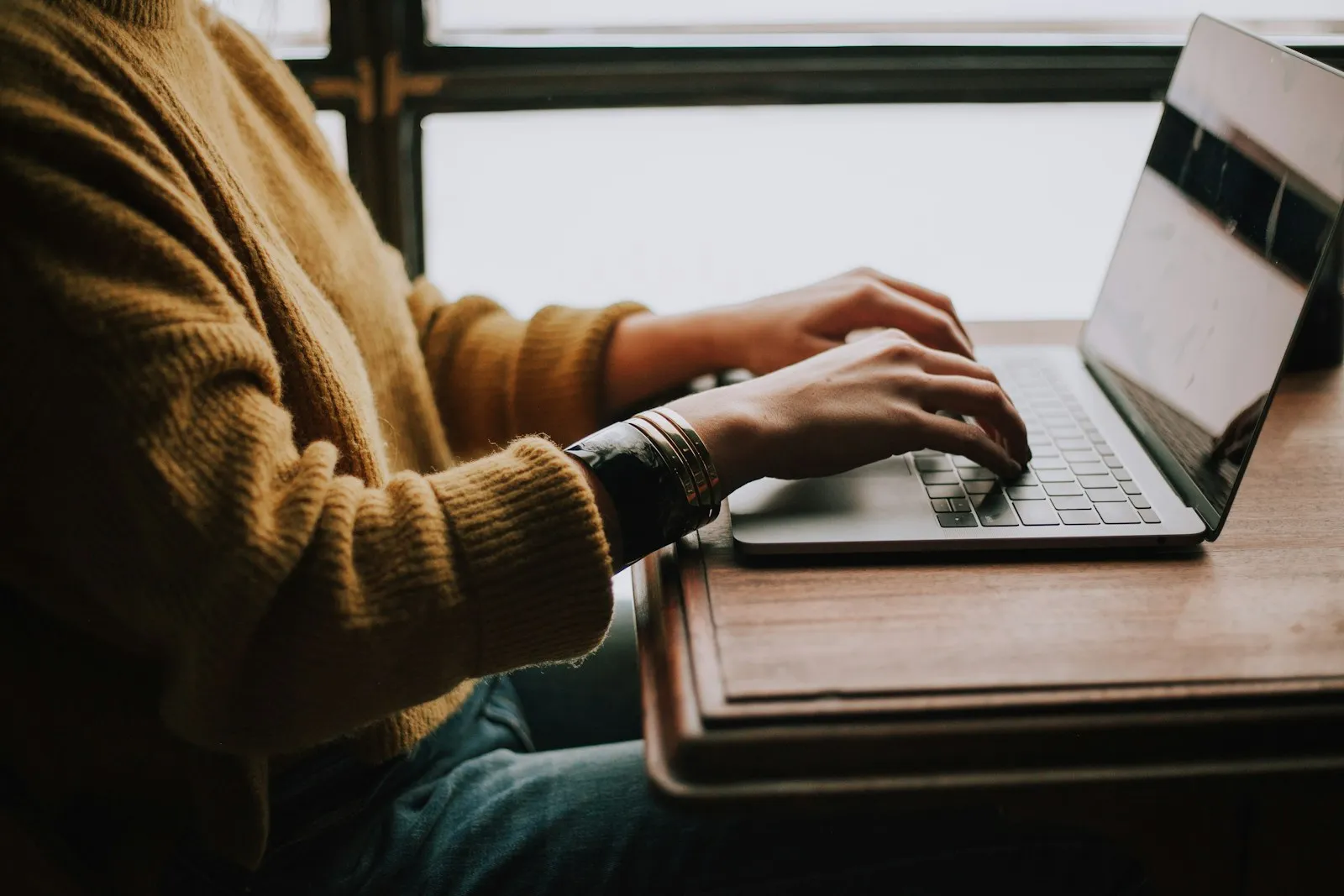 A person at a desk looking closely at an email on a laptop screen