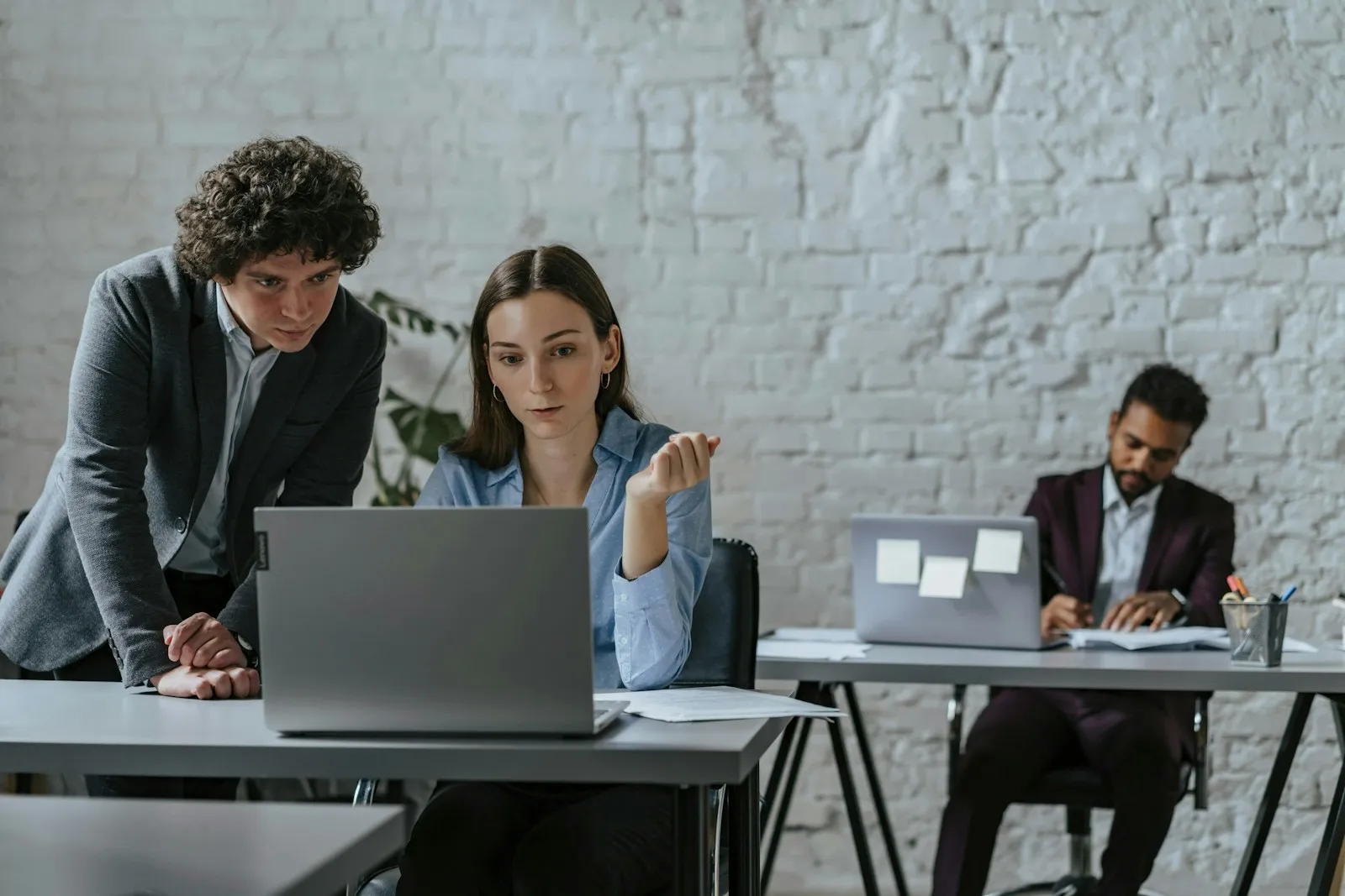 A small group of office staff gathered around a laptop during a hands-on software training session
