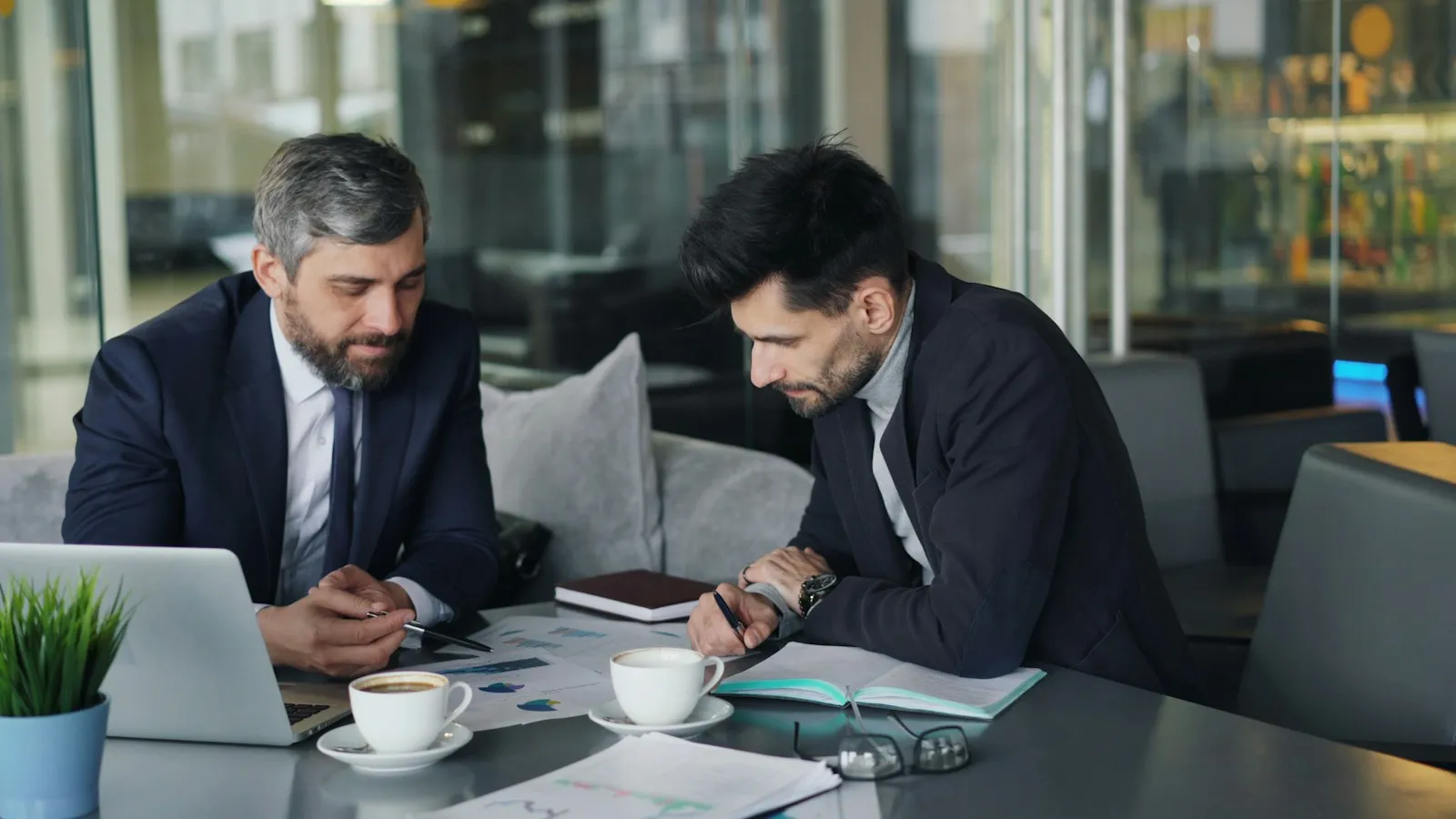 Two businessmen reviewing paperwork together at a table