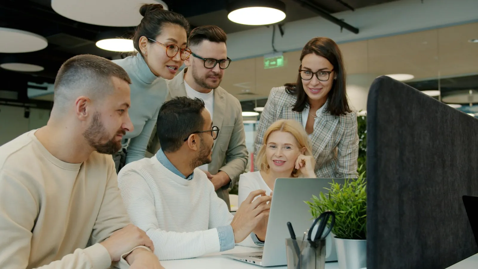 Team gathered around a laptop collaborating in an office