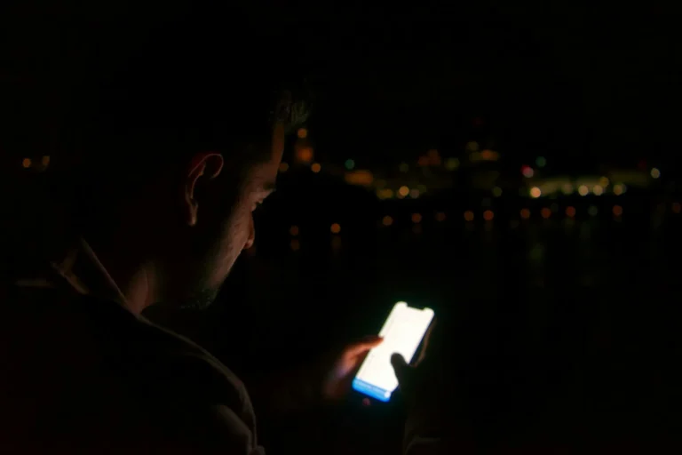 A person in a dim room looking at a smartphone screen lit up with notifications